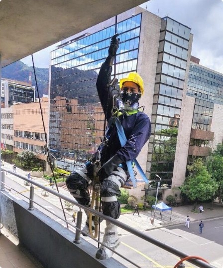 Técnico en trabajo de alturas con rapel sobre la fachada de un edificio